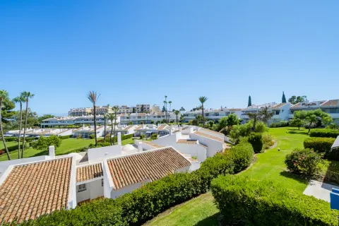 Gardens and tiled roofs under a blue sky, seen from a terrace