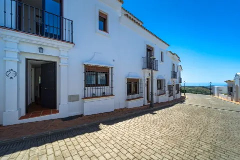 A street of white houses with iron balconies, the sea at its end