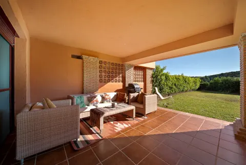 A covered terrace with wicker sofas, opening onto a lawn
